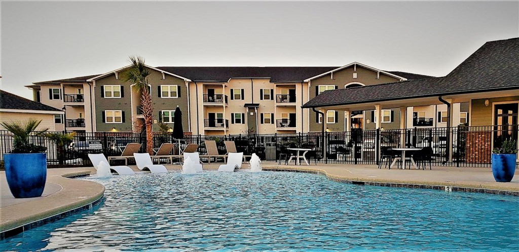a swimming pool with chairs and a building in the background