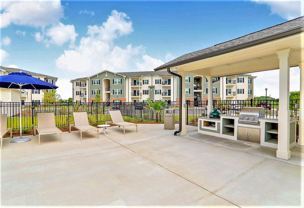 a patio with chairs and tables and a grill