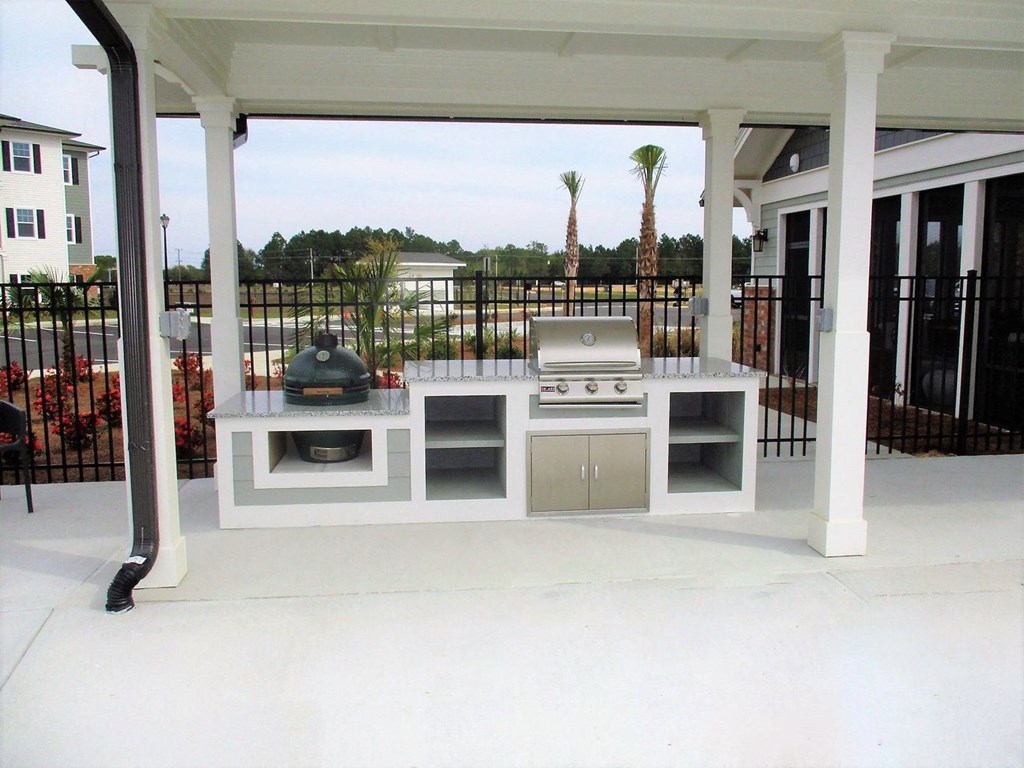 a white outdoor kitchen with stainless steel appliances on a patio
