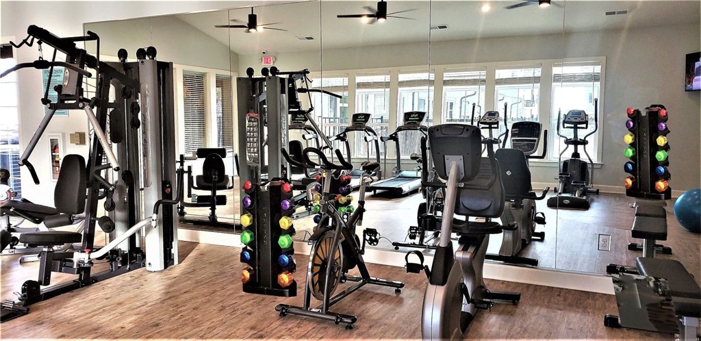 a home gym filled with exercise equipment and windows