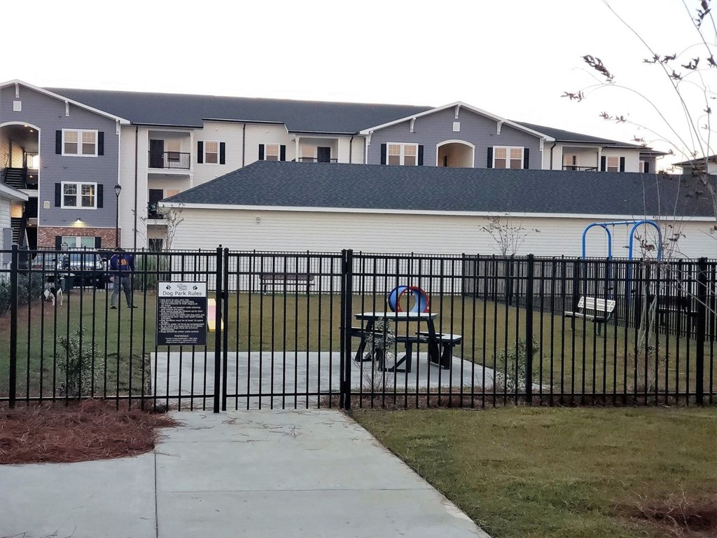 a playground with a fence in front of an apartment building