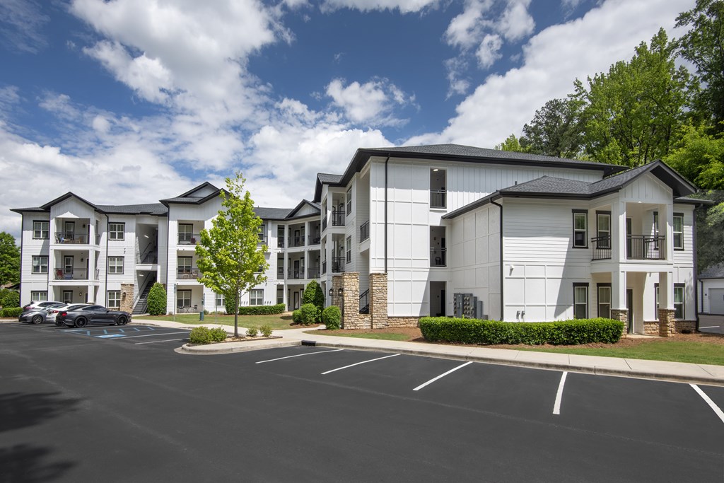 A parking lot in front of a white apartment building.