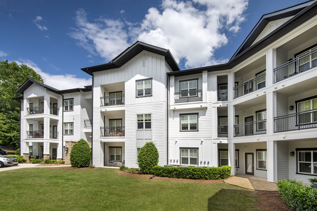 A white apartment building with balconies and a green lawn in front.