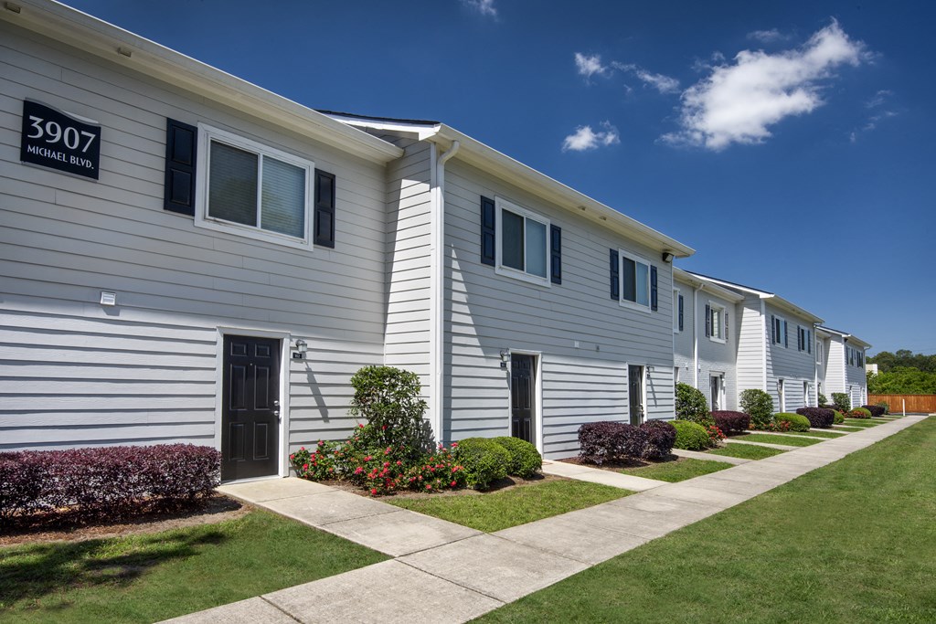 a white house with a sidewalk and lawn in front of it