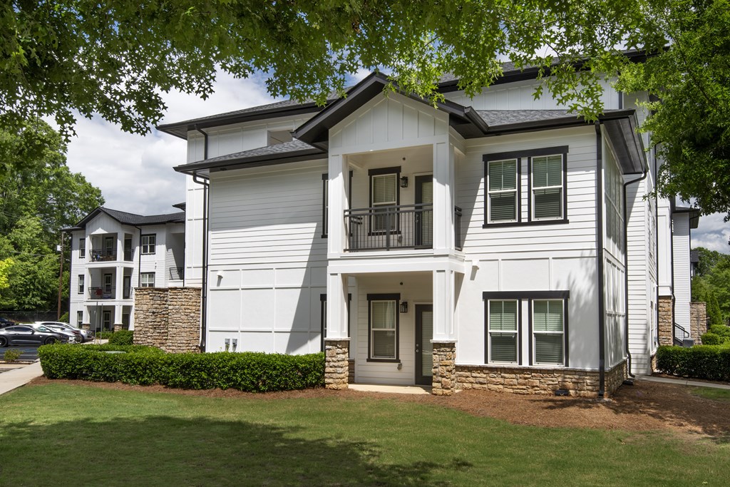 A white two-story house with a stone pillar and a black door.