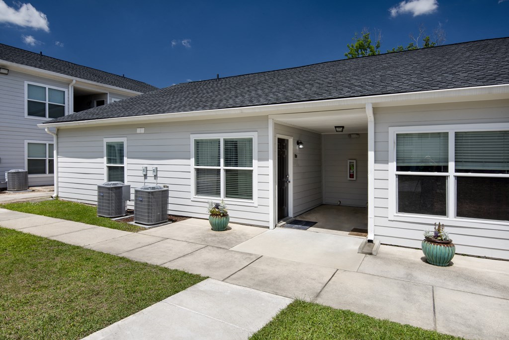 the front of a white house with a concrete sidewalk and grass