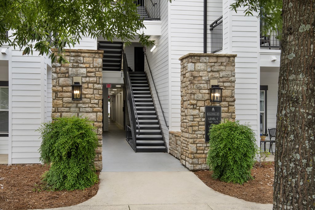 A white building with a stone pillar and a black sign on it.