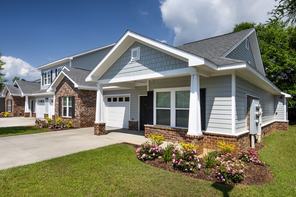 a blue house with a lawn and flowers in front of it