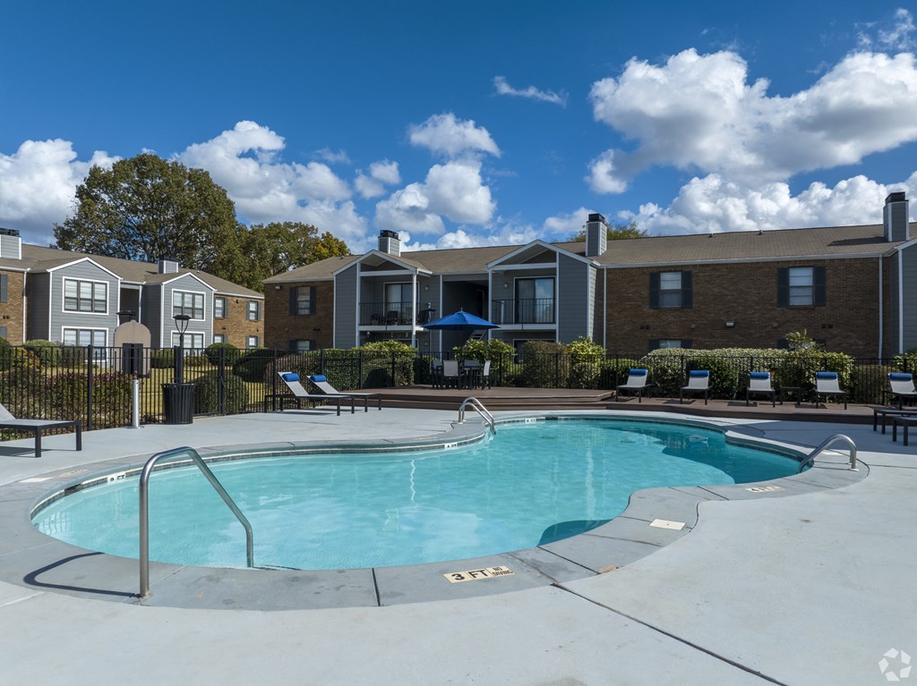 A swimming pool surrounded by a fence and chairs.