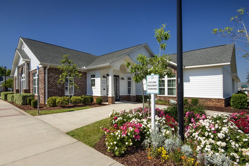 a white house with a sign in front of a flower garden