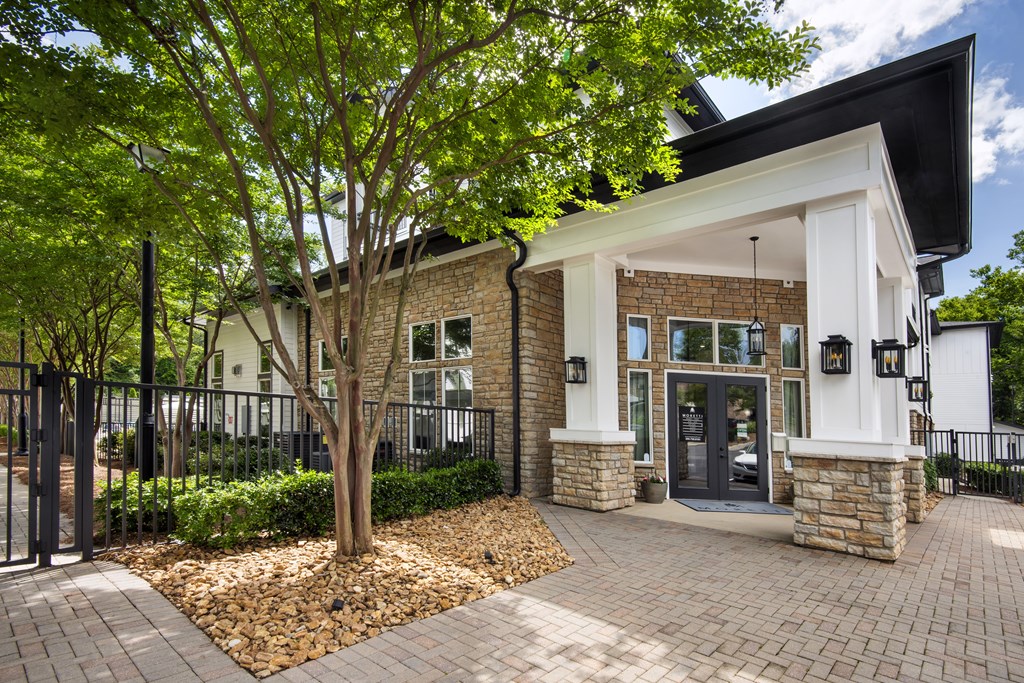 A modern house with a black roof and a stone pillar entrance.
