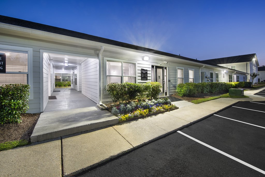 the exterior of a white building with a driveway and landscaping