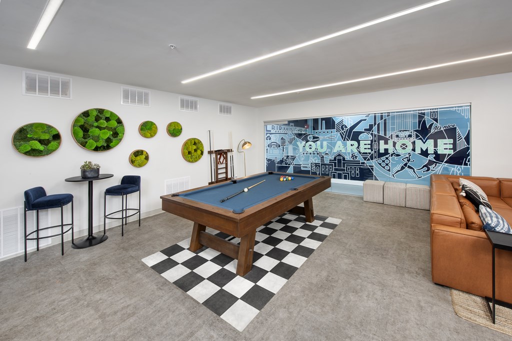A pool table in a room with a blue couch and a wall with green circles.