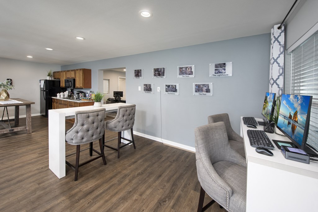 a home office with a desk and chairs and a kitchen
