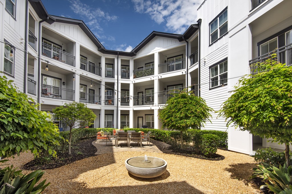 A courtyard with a fountain surrounded by white buildings.