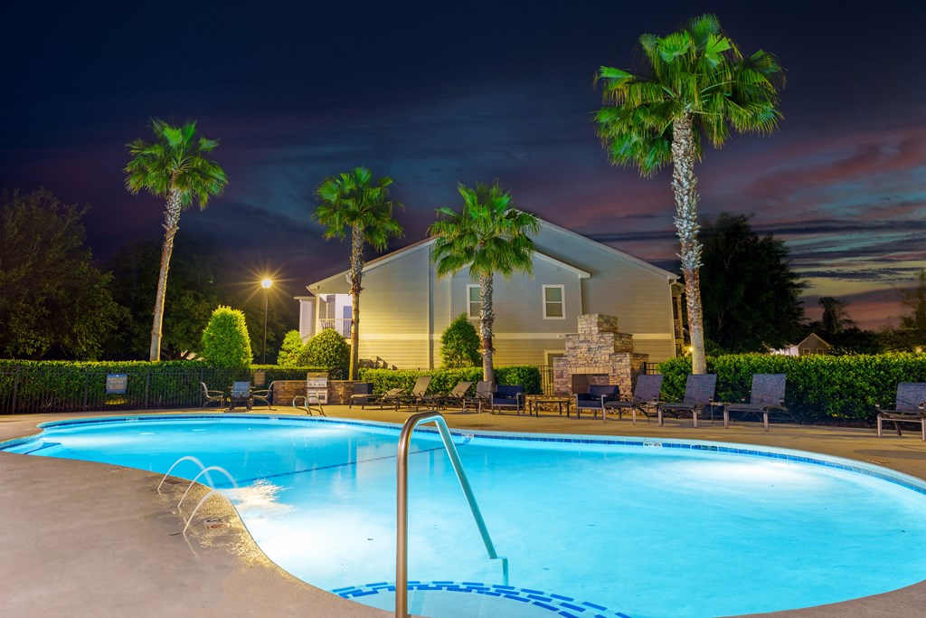 a swimming pool at night at a resort with palm trees