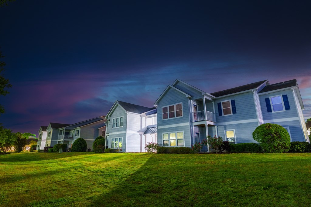a row of houses on a green lawn at night
