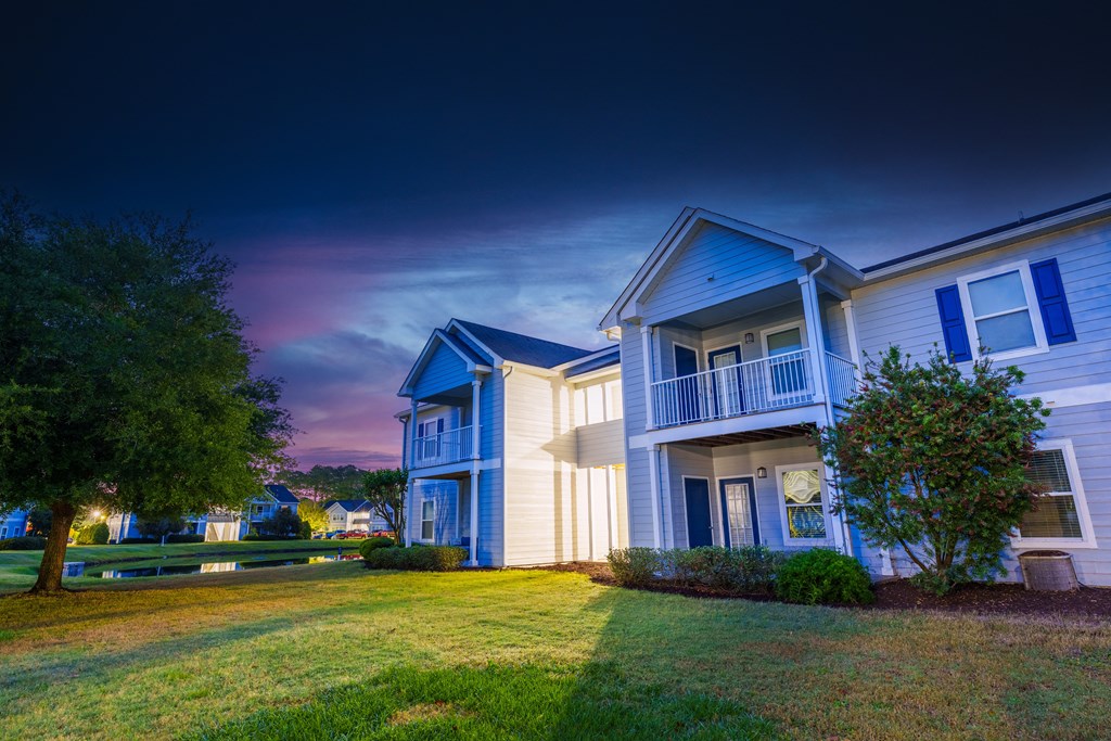 a row of houses with a green yard and a cloudy sky
