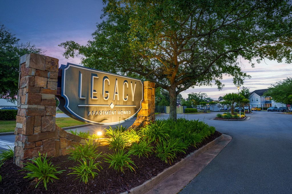 a sign at the entrance to legacy apartments at dusk
