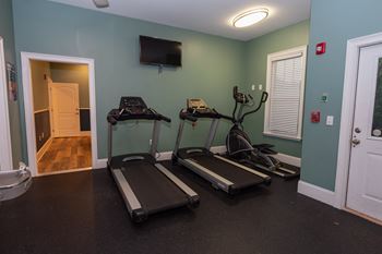 two treadmills and a tv in a gym room