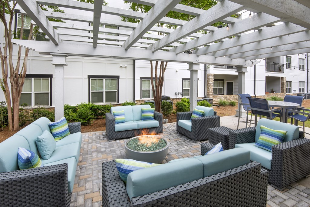 A patio with a fire pit and wicker furniture.