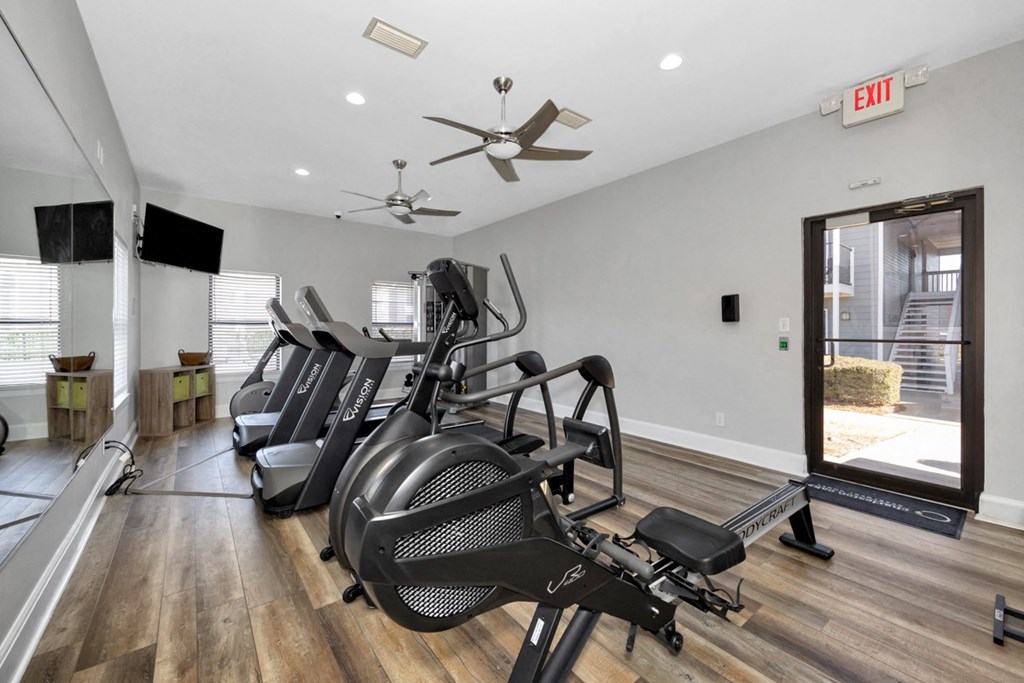 A gym with treadmills, elliptical machines, and a fan.