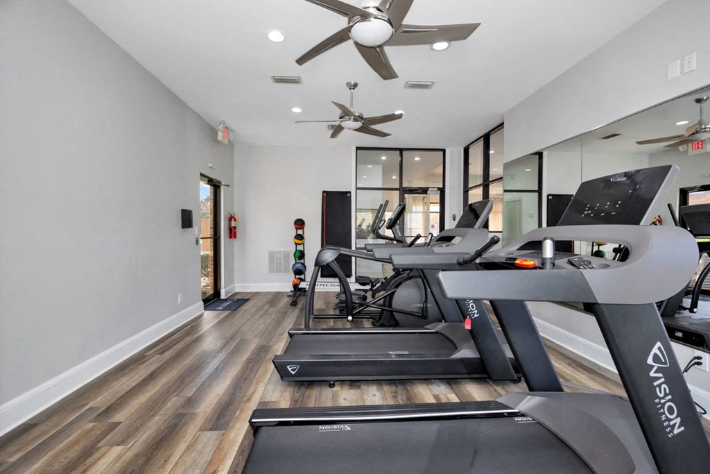A gym with treadmills and a fan.