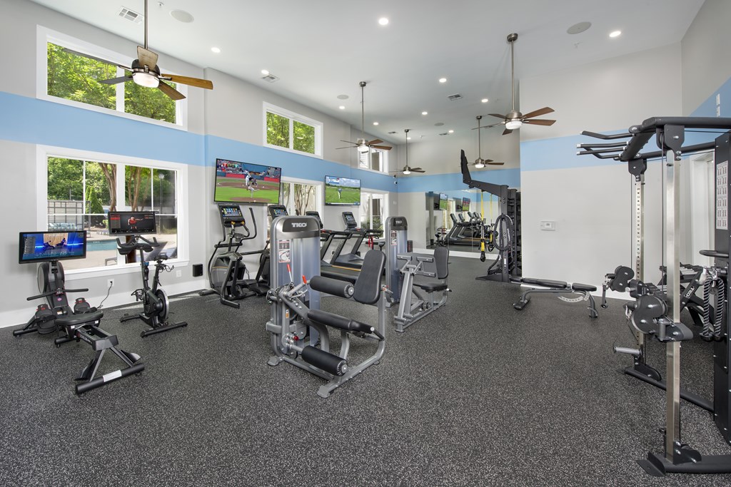A spacious gym with a variety of equipment and a television screen.