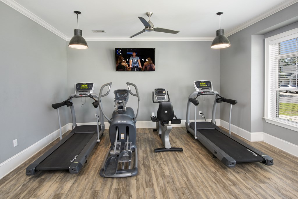 a gym with four treadmills and a tv on the wall