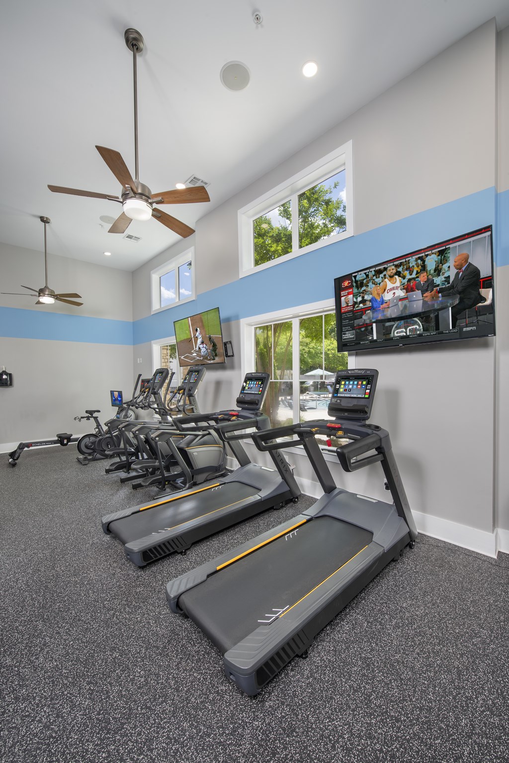A room with treadmills and a television mounted on the wall.