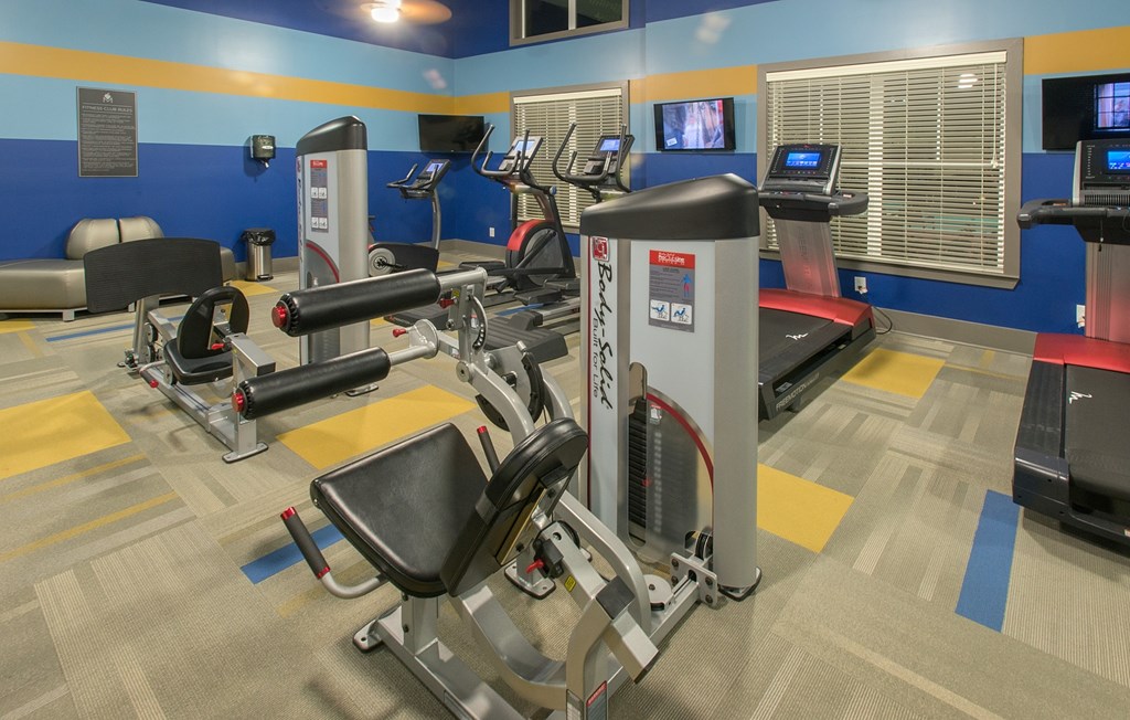 A gym with a row of treadmills and exercise machines.