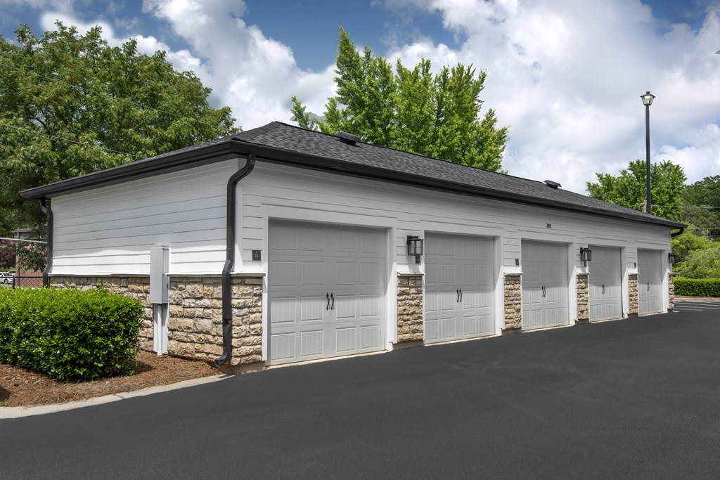 A white building with a black roof and four garage doors.