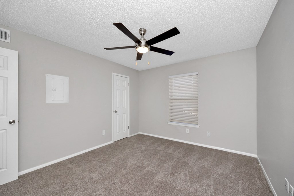A room with a ceiling fan and carpeted floor.