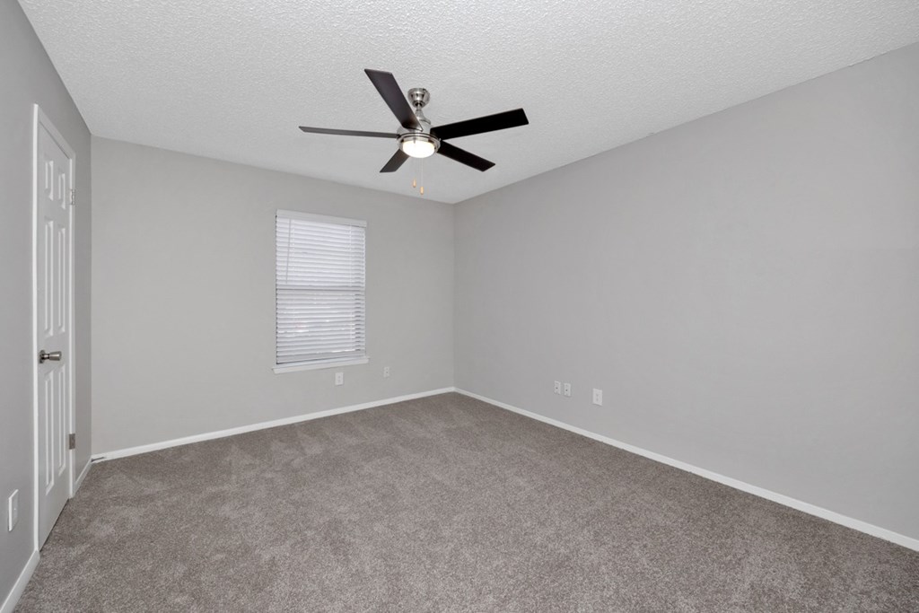 A room with a ceiling fan and carpeted floor.