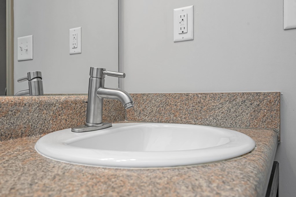 a sink in a bathroom with a faucet and a mirror