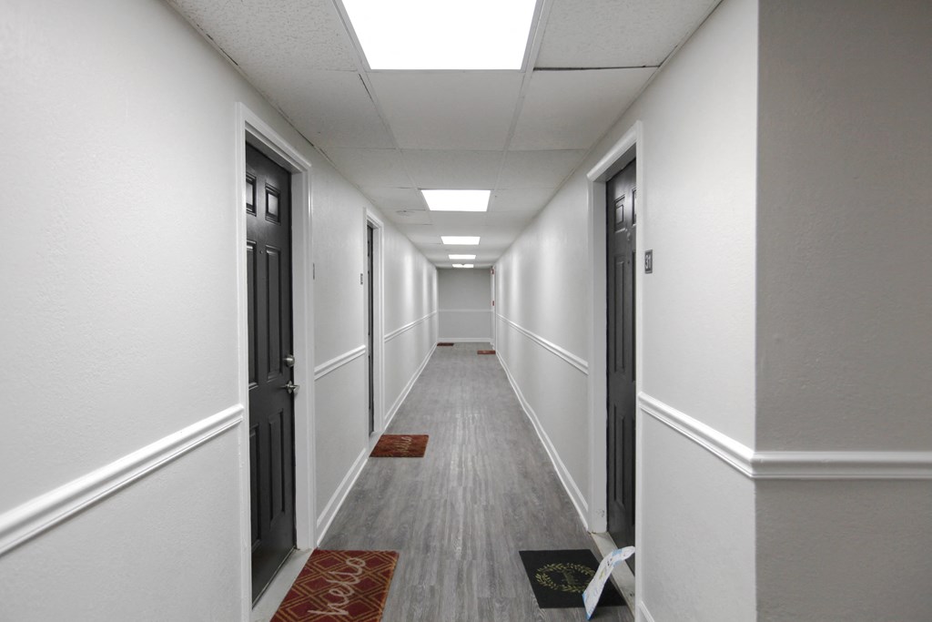 a long corridor with white walls and grey floors