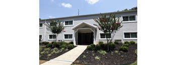 a gray building with a sidewalk and trees in front of it