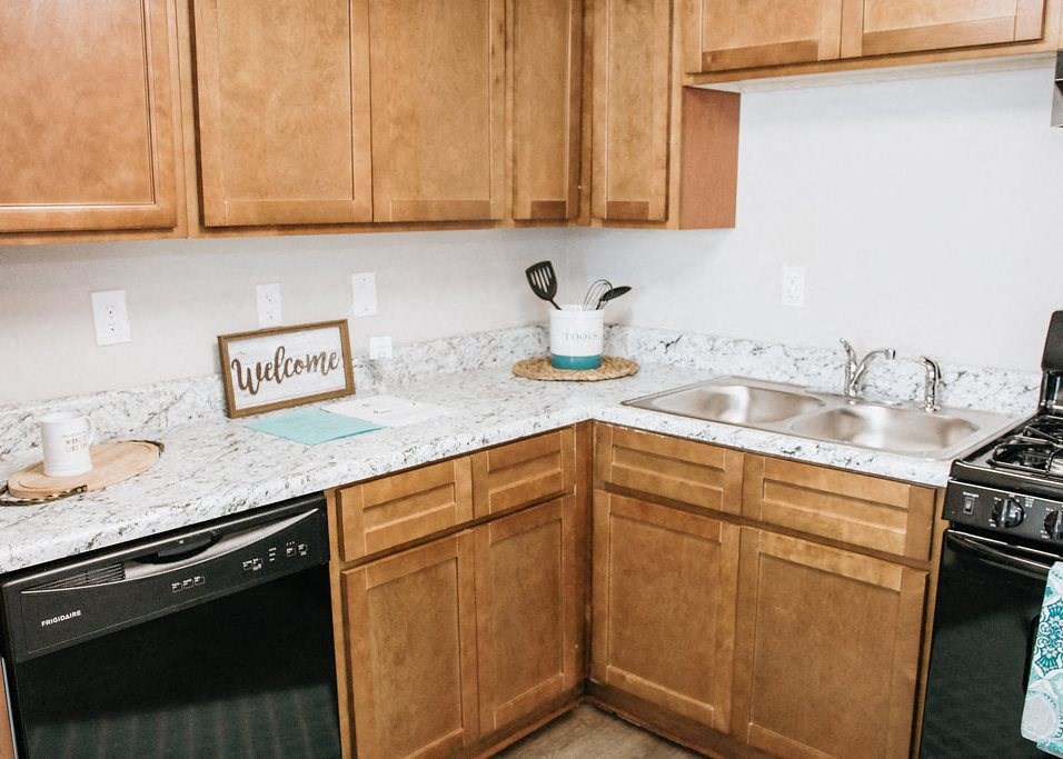 a kitchen with wooden cabinets and a black dishwasher