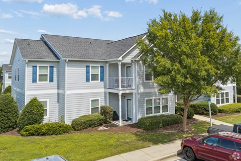 A two-story house with a red car parked in front.