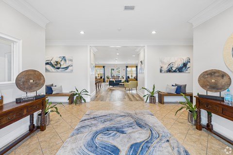 A large, open living room with a blue and white rug in the center.