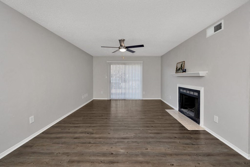 A spacious living room with a fireplace and a ceiling fan.