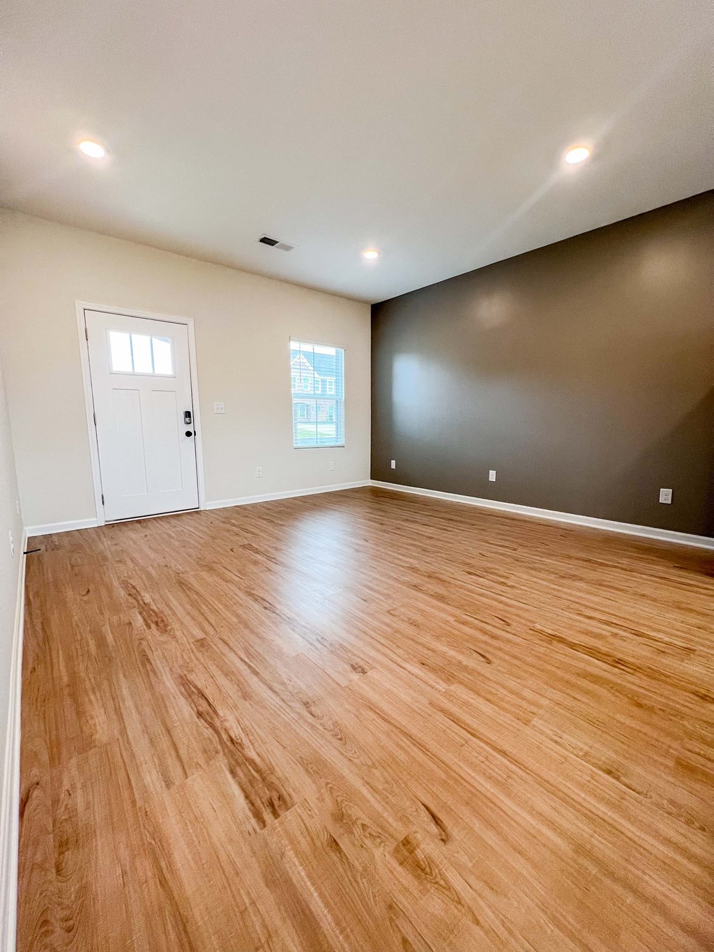 an empty living room with wood floors and a black wall