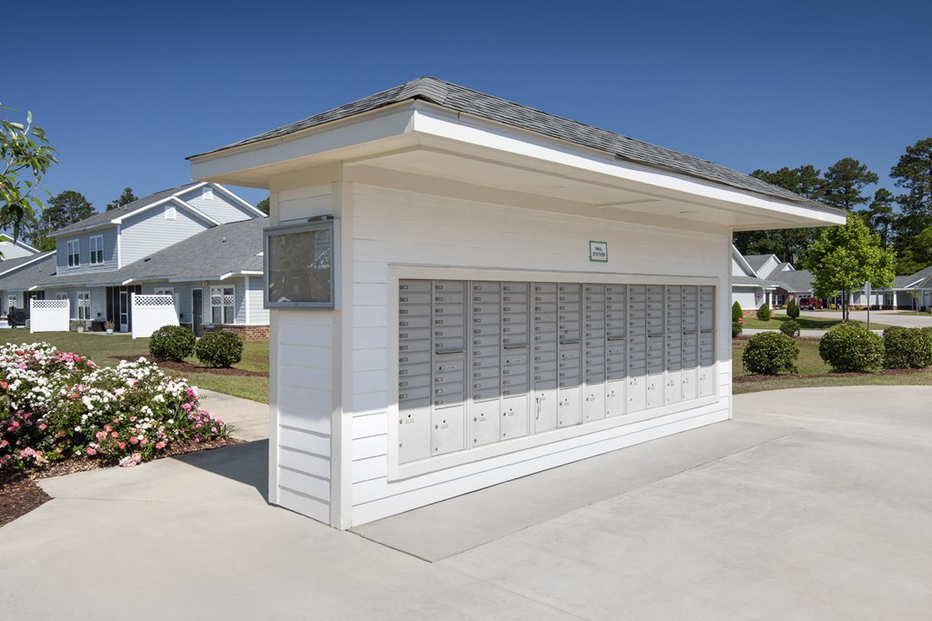 a small garage with a white building with a driveway
