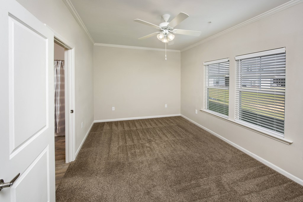 an empty living room with carpet and a ceiling fan