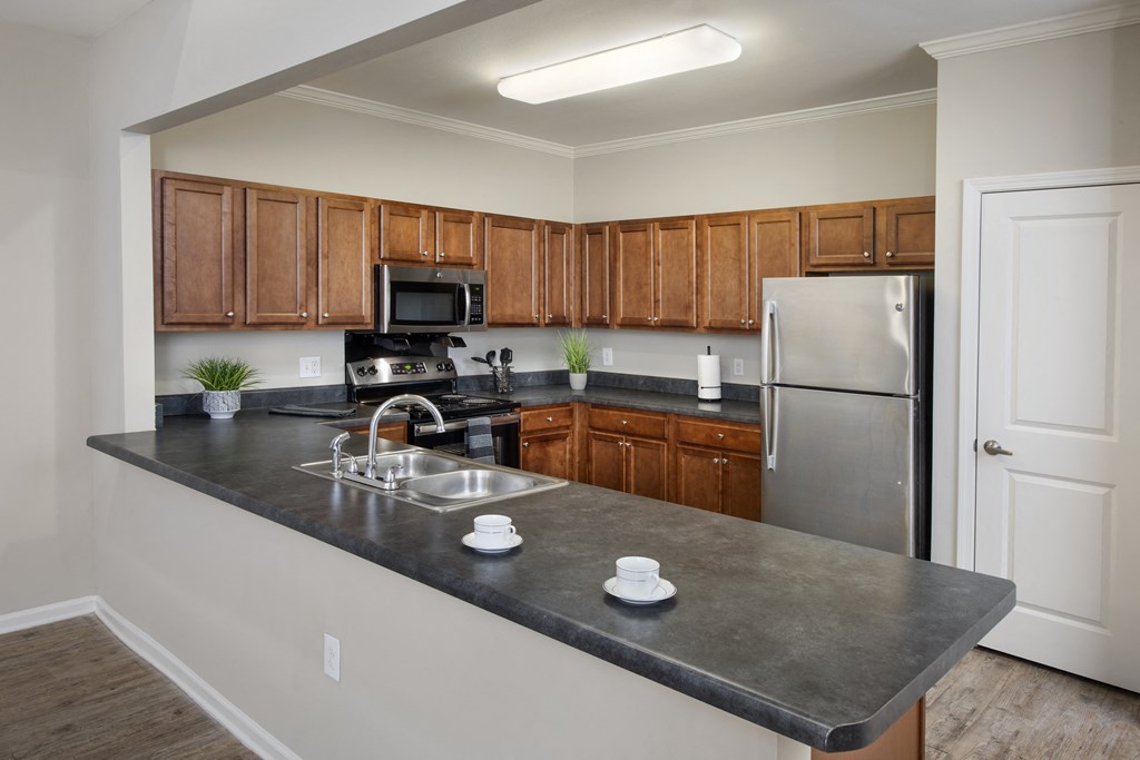 an empty kitchen with stainless steel appliances and wooden cabinets