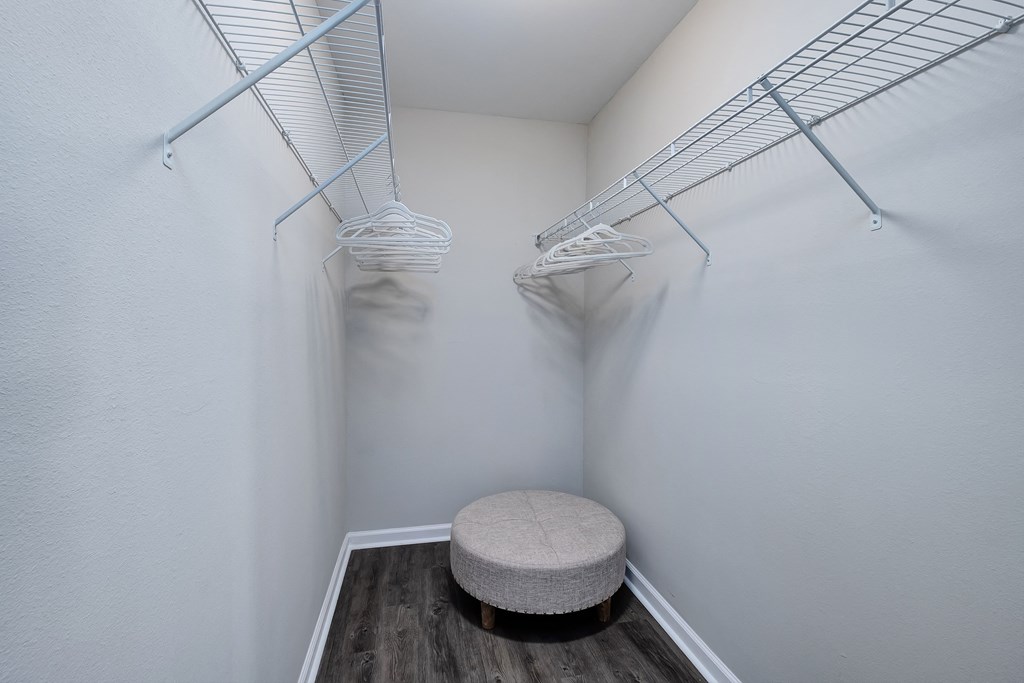 an empty closet with a stool in the corner of a room