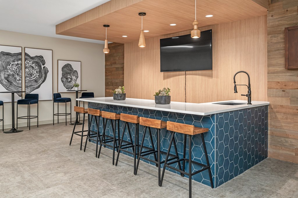 a communal kitchen with bar stools and a tv