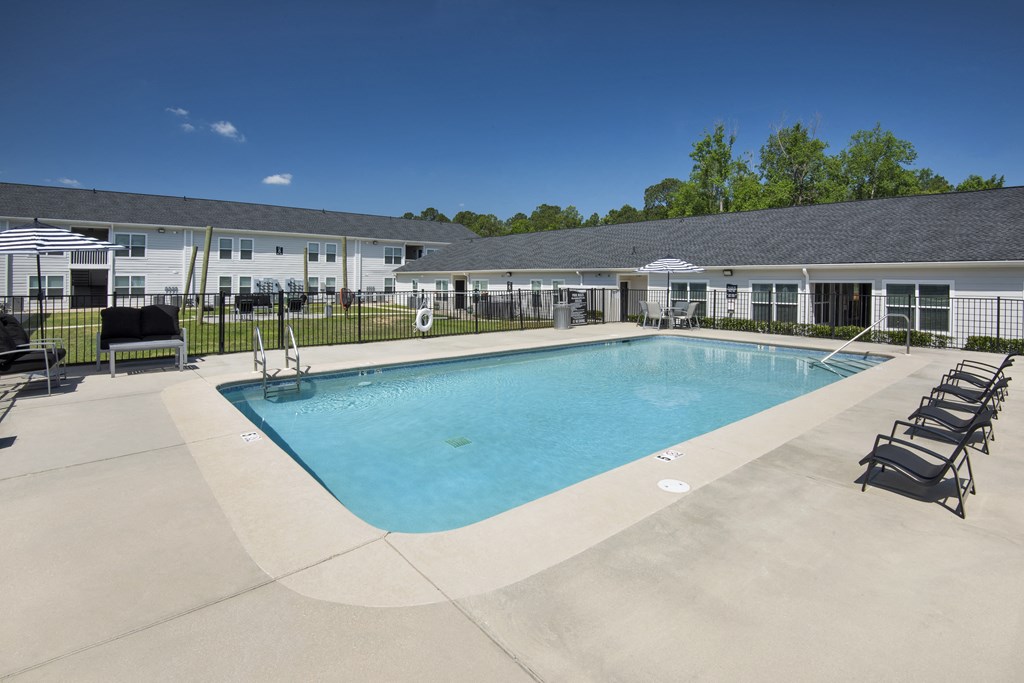 a swimming pool with chairs around it in front of a building