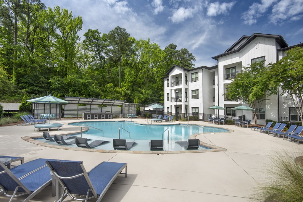 A large swimming pool surrounded by lounge chairs and trees.