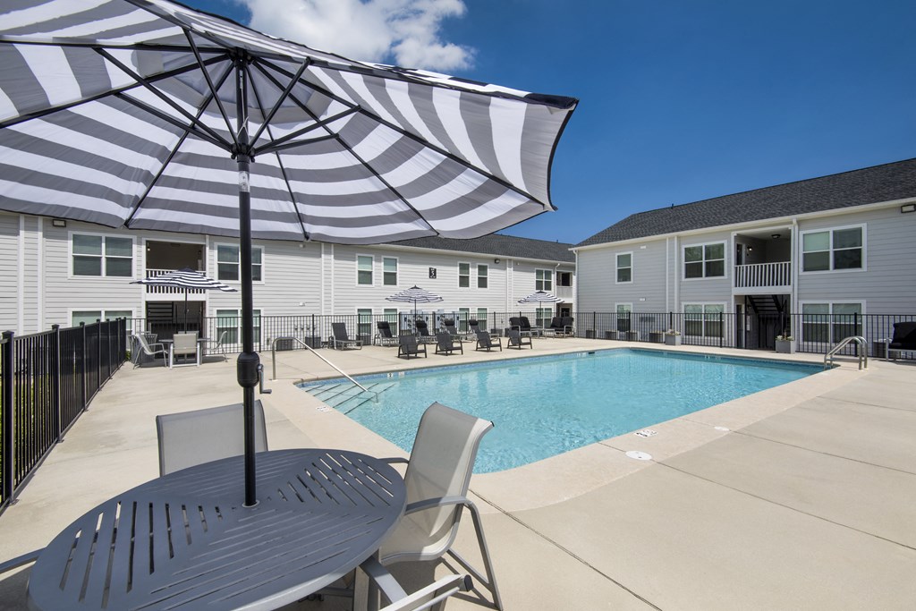 our apartments have a large pool and patio with chairs and an umbrella